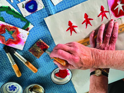 a person dabbing a paintbrush on a sponge between stencils.
